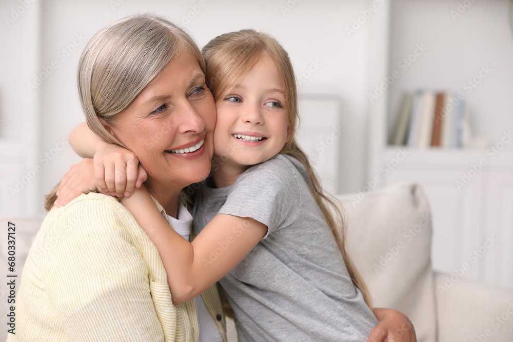 Happy grandmother hugging her granddaughter at home, space for text Happy grandmother hugging her granddaughter at home, space for text