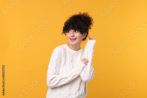 Happy young woman in stylish white sweater on yellow background © New Africa