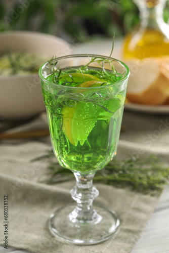 Delicious drink with tarragon in glass on white table