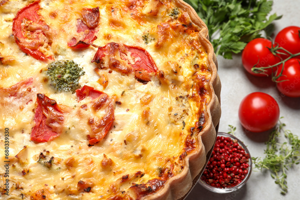 Tasty quiche with tomatoes and cheese served on light table, closeup