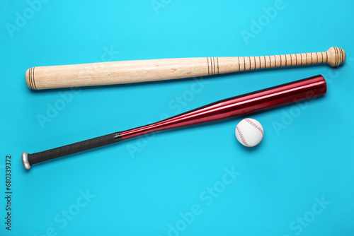 Baseball bats and ball on light blue background, flat lay