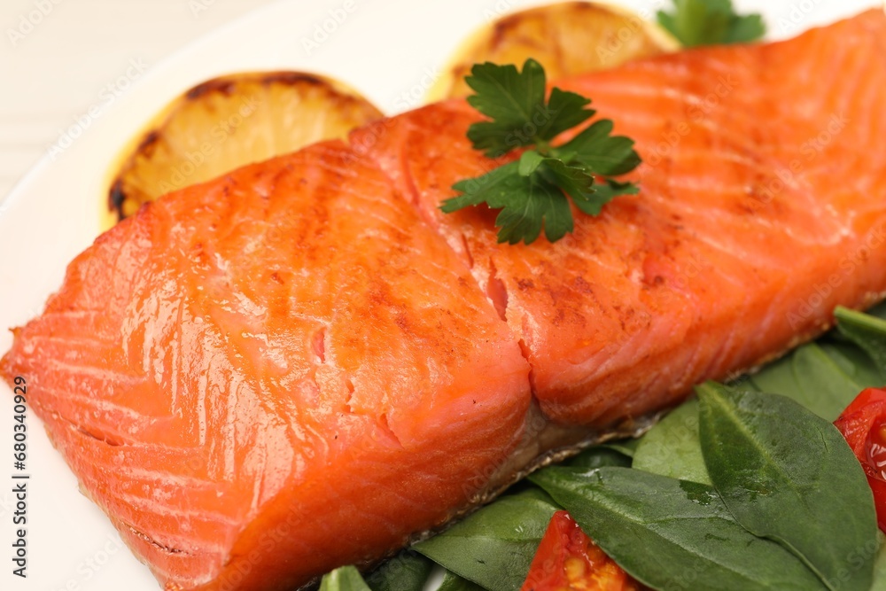 Tasty grilled salmon with basil and parsley on white plate, closeup
