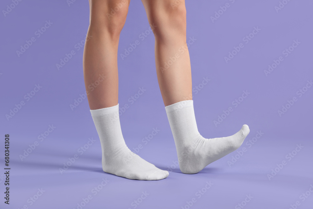 Woman in stylish white socks on violet background, closeup Woman in stylish white socks on violet background, closeup