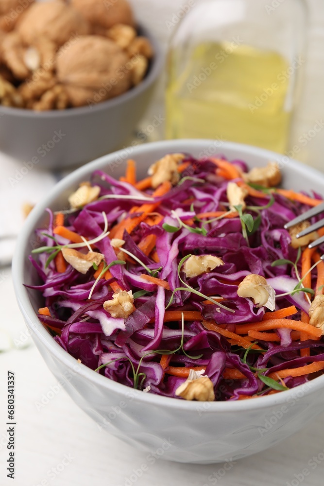 Tasty salad with red cabbage and walnuts at white table, closeup