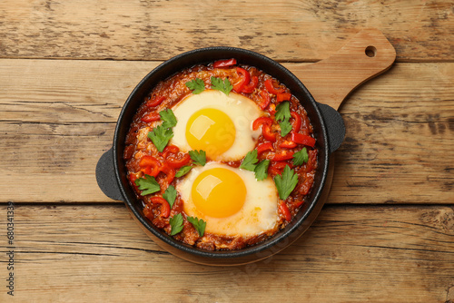 Delicious Shakshuka on wooden table, top view
