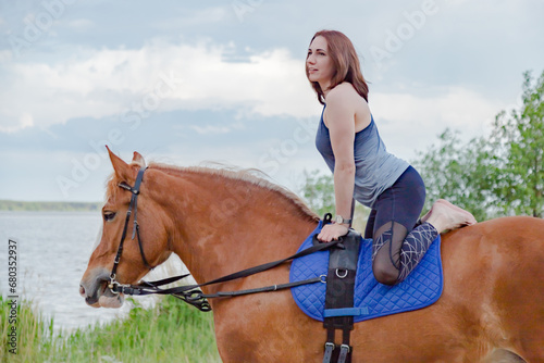 young woman doing yoga on a horse against the backdrop of trees