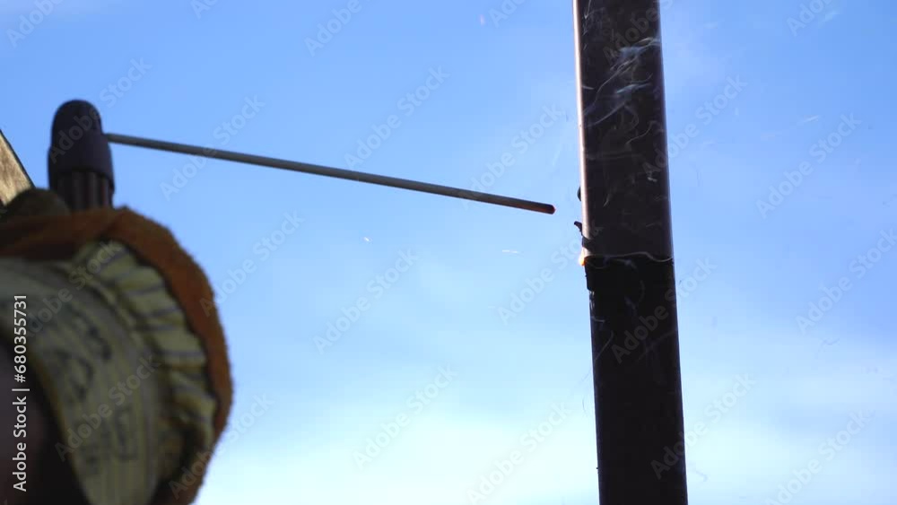 Welder at work in metal industry, welding metal construction. Male welder is welding a thick steel pipe with an electrode. Welder at work in metal industry, welding metal construction. Male welder is welding a thick steel pipe with an electrode.