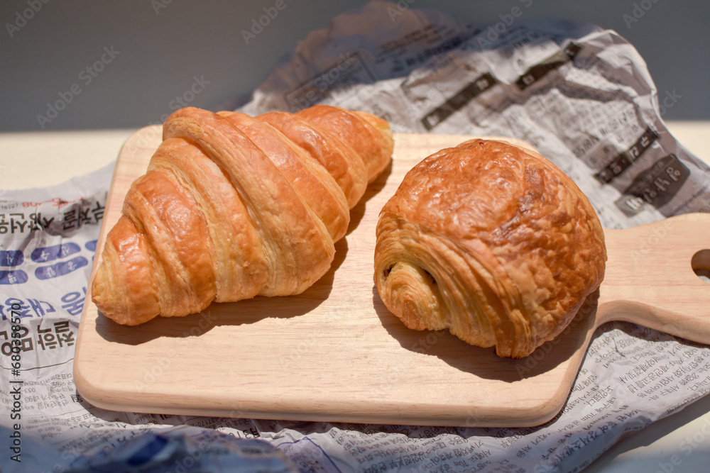 Close up bakery on news papers background- yeasted puff pastry dough wrapped around a stick of chocolate Close up bakery on news papers background- yeasted puff pastry dough wrapped around a stick of chocolate