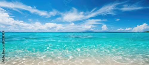 picturesque landscape of a white sandy beach, people bask summer sun, surrounded by the beauty of nature the azure sea, clear sky, and fluffy white clouds background.