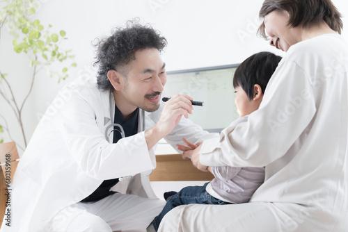 小児科医の男性医師に診察を受ける子ども 口をあける