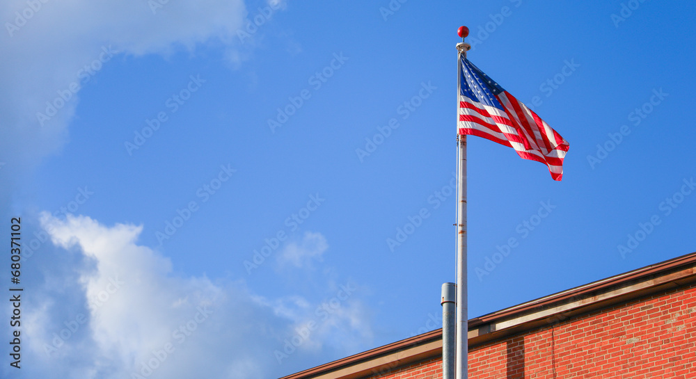 US flags waving against clear blue sky, symbolizing patriotism, unity, freedom, and national pride in a bustling cityscape