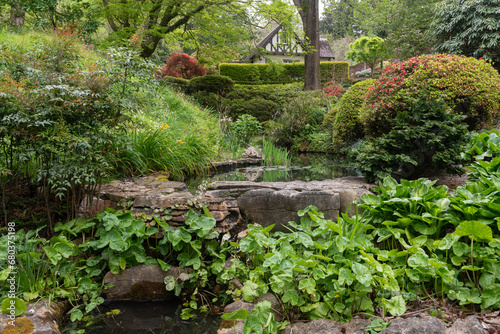 Water feature set in a lush garden setting. Small pond retained behind a rough stone dam