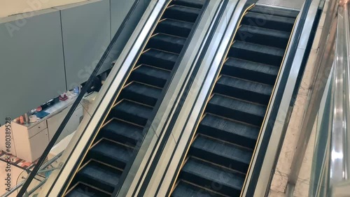 Escalator in a building close up. The escalator is empty, and the steps move up and down. The escalator is flanked by two walls, one on the left and one on the right