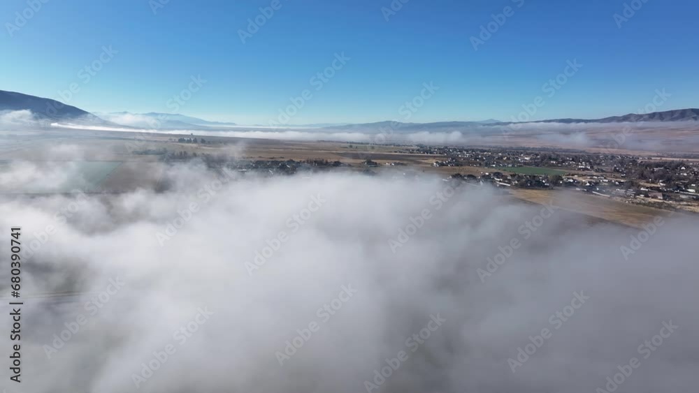 Aerial over fog clouds farm town valley fast. Late autumn fall inversion thick layer of low clouds and fog. Rural town mountain valley. Cool weather environment. Farms, fields, village, agriculture. Aerial over fog clouds farm town valley fast. Late autumn fall inversion thick layer of low clouds and fog. Rural town mountain valley. Cool weather environment. Farms, fields, village, agriculture.