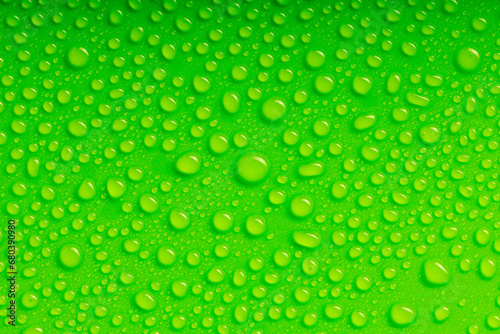 top view of a bright green surface with water droplets of various shapes