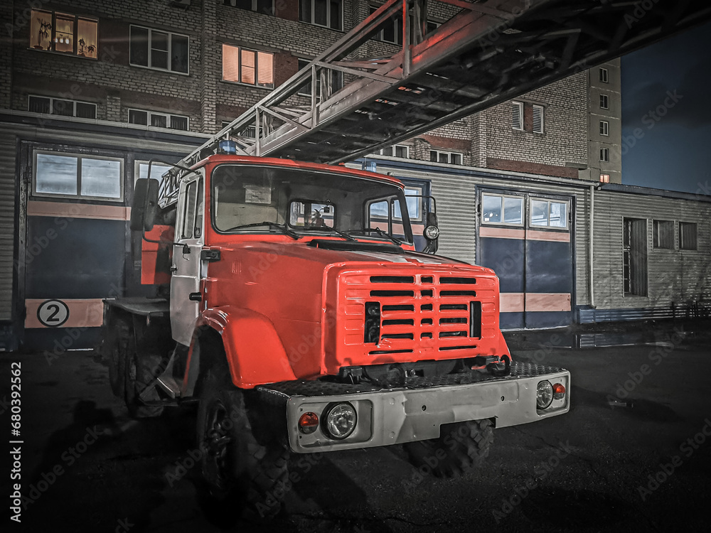 Old firetruck on the background of an old building at night