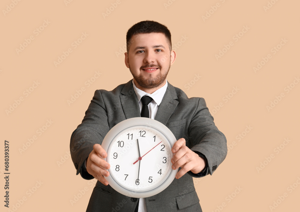 Young happy businessman with clock on beige background. Time management concept Young happy businessman with clock on beige background. Time management concept