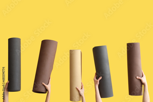 Female hands with yoga mats on yellow background photo