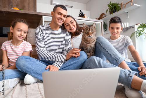 Happy family with cat and laptop in kitchen