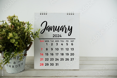 January 2024 monthly calendar with vintage alarm clock on wooden background