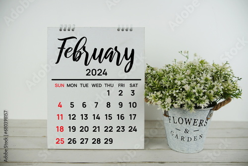 February 2024 monthly calendar with vintage alarm clock on wooden background