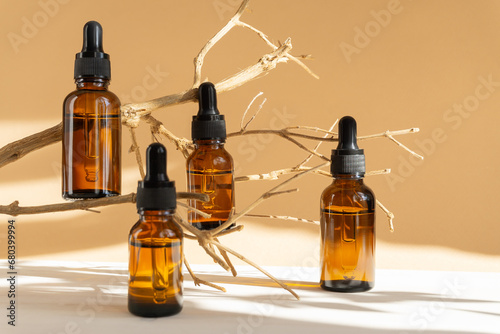 Serum in amber-colored glass vials with dropper lid on brown background. Essential oil for care of women's skin in rays of sunlight. Concept of beauty, rejuvenation, mockup. photo