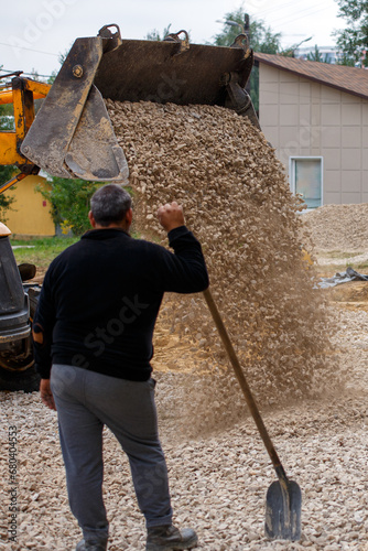 Obraz na płótnie a bulldozer pours macadam from a bucket onto the ground at a construction site i