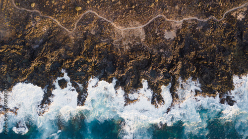 Drone view of Tenerife south coast with Atlantic ocean and strong swell beating against the walls of a rocky cliff, blue rough sea with big waves with foam crashing against the rocks © luciano
