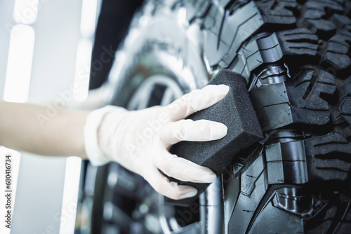 Professional car service worker polishing car tires with black sponge photo