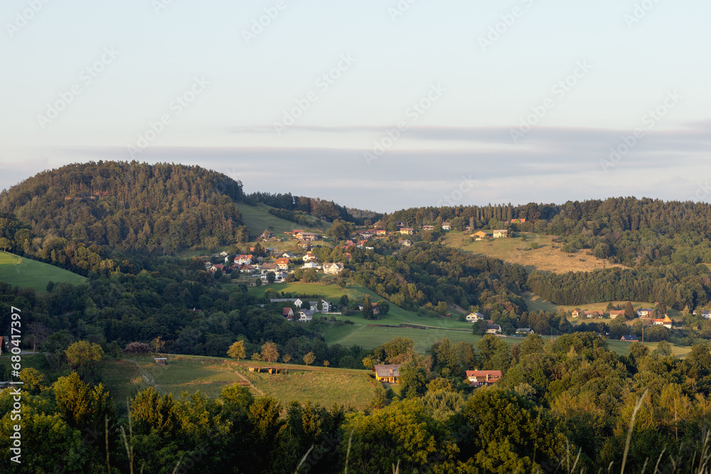 A village in a valley between hills in the middle of a forest