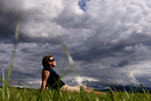 A tourist is resting on a field under dark low clouds