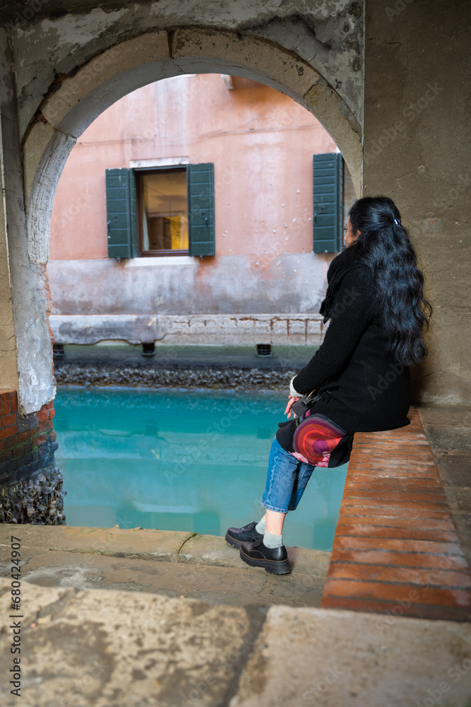 Venetian glimpse with silky water and lagoon colours. Smiling and sitting woman with long hair