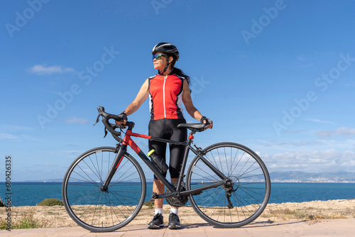Female cyclist standing in front of her bicycle looking to the right of her. Concept of sporty, active, happy woman