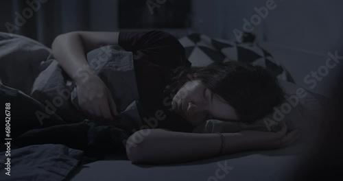 Woman sleeping soundly in bed at night in dark room photo