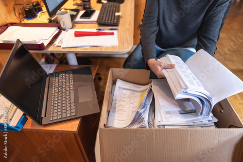 Woman saving and filing company documents in cardboard boxes while teleworking.