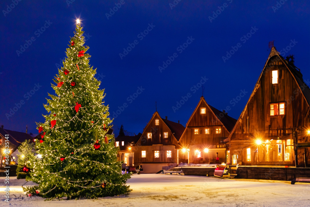 New Year. New Year tree on the square in the center of the town, wooden houses and the night sky in the background. festive mood and atmosphere concept New Year. New Year tree on the square in the center of the town, wooden houses and the night sky in the background. festive mood and atmosphere concept