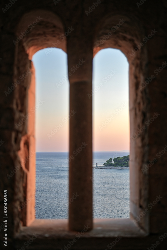 Blick durch Turmfenster aufs Meer im Sonnenuntergang Blick durch Turmfenster aufs Meer im Sonnenuntergang