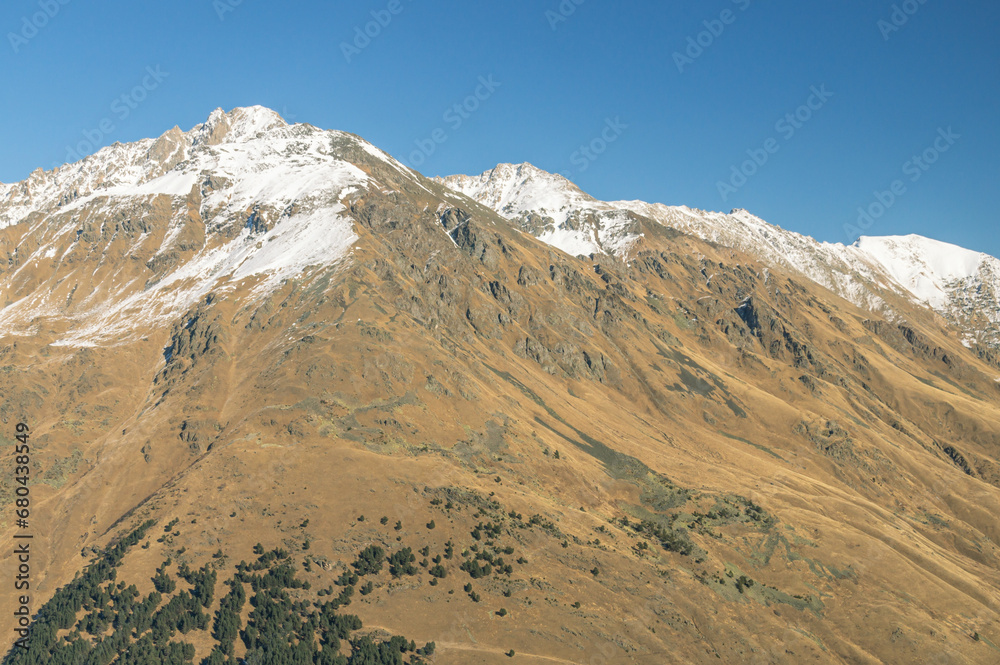 Panoramic view of snow-capped mountain peaks in clear sunny weather. Vacation at a ski resort high in the mountains. Clean air in the mountains. Outlines of mountains with icy peaks.