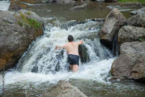 Back view of man in small waterfall.