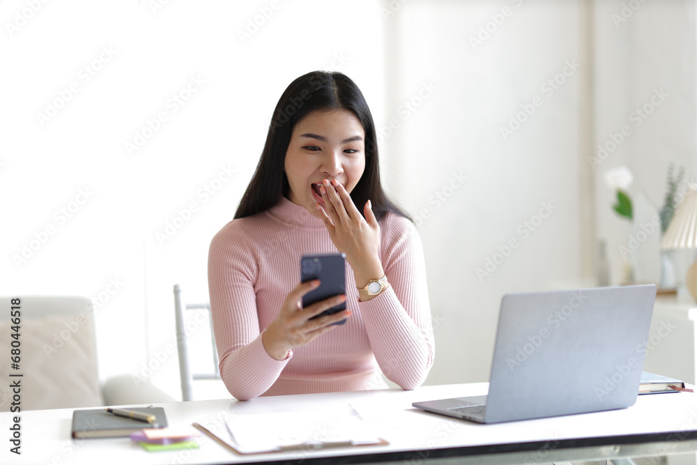 Attractive young Asian woman using smartphone in office at home. Attractive young Asian woman using smartphone in office at home.