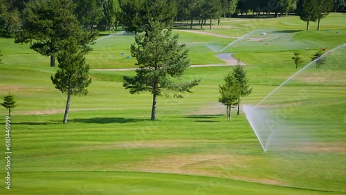 Automatic high-pressure water sprinkler at green golf course watering the grass.