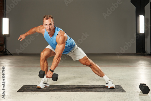 Caucasian athlete trains his legs with a dumbbell in his hand. fitness. aerobics. exercises on the mat. physical health