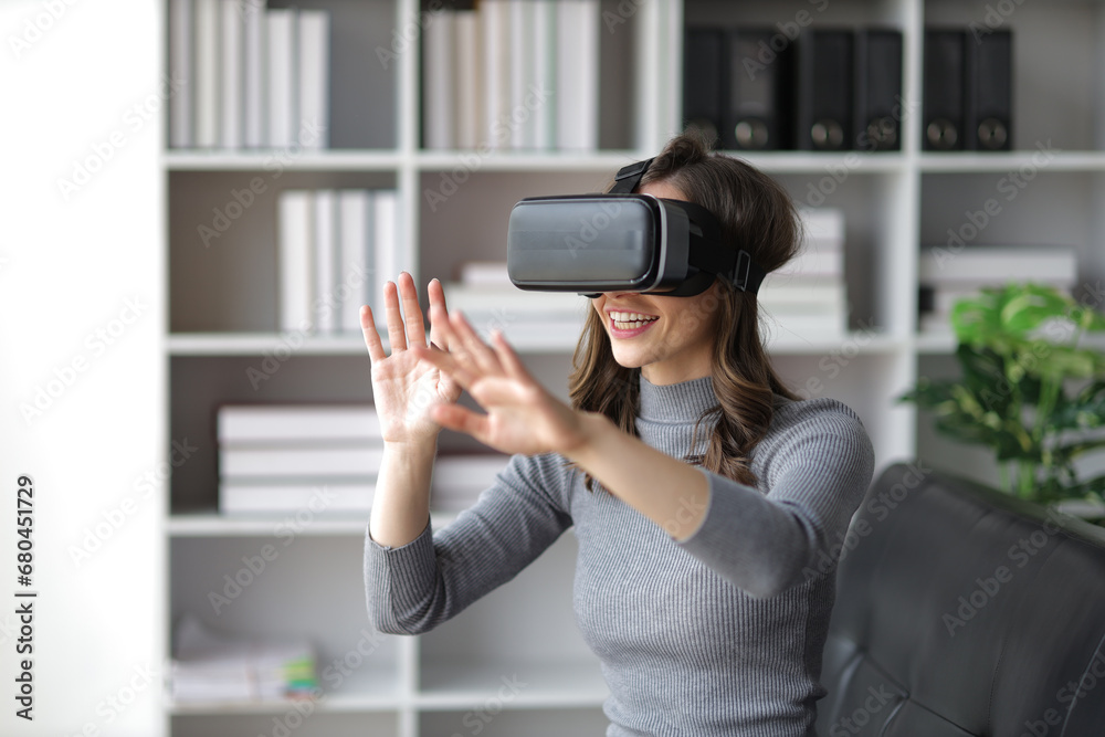 A woman sitting on a sofa in the living room wearing VR 3D glasses looks excited about a movie. A woman sitting on a sofa in the living room wearing VR 3D glasses looks excited about a movie.