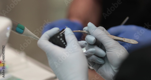Doctor's hands with a working tool. Preparation and process of dental treatment. Dental instrument in the office of a modern dentist. Close-up in 4K, UHD photo