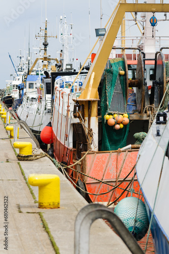 A line of trawlers berthed at a harbour wharf.