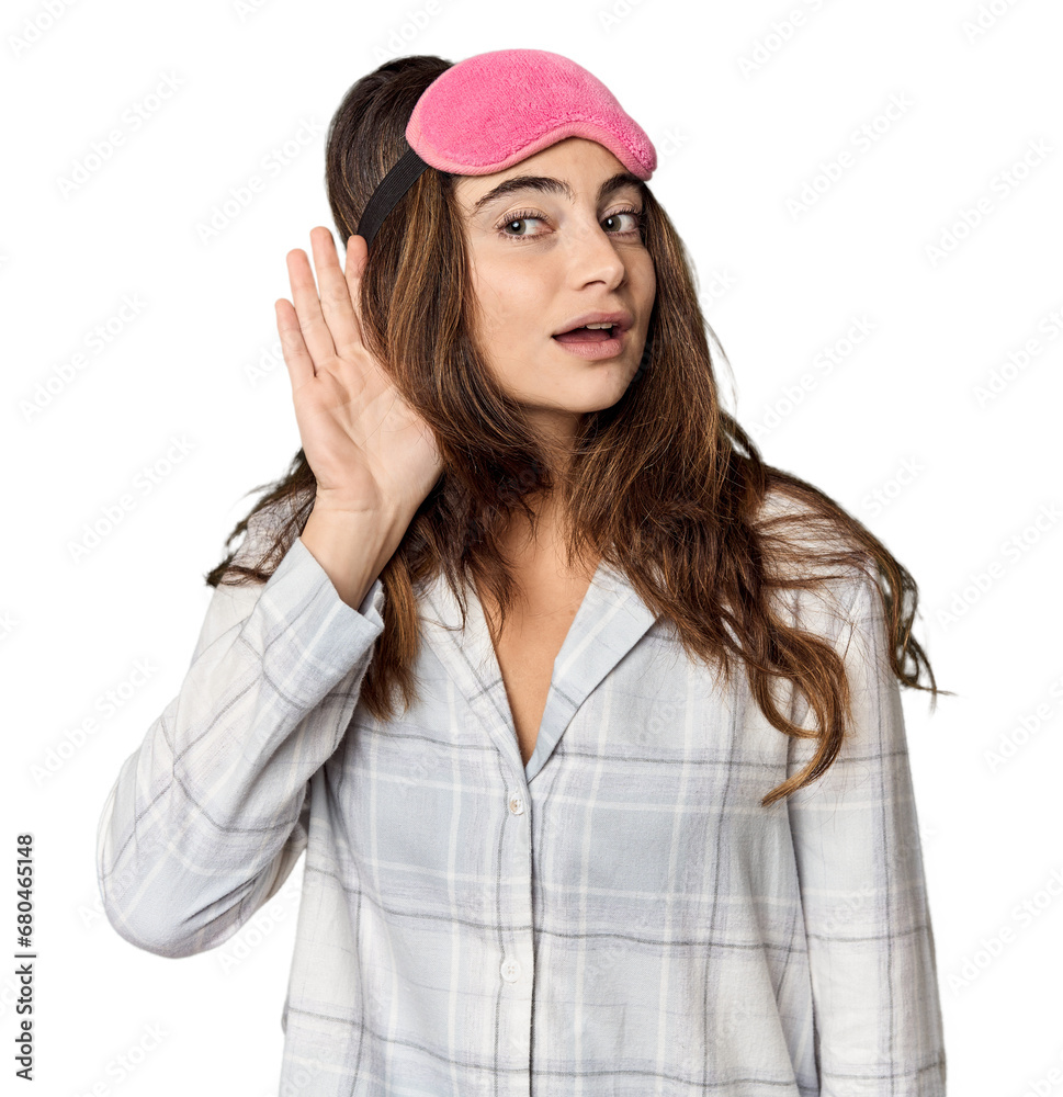 Young Caucasian woman in pajamas with mask trying to listening a gossip. Young Caucasian woman in pajamas with mask trying to listening a gossip.