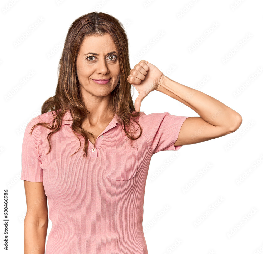 Middle-aged woman portrait in studio setting showing a dislike gesture, thumbs down. Disagreement concept. Middle-aged woman portrait in studio setting showing a dislike gesture, thumbs down. Disagreement concept.