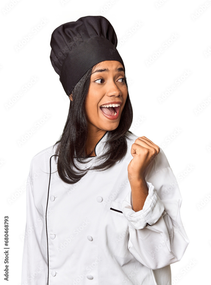 Young Filipina chef with cooking hat in studio points with thumb finger away, laughing and carefree. Young Filipina chef with cooking hat in studio points with thumb finger away, laughing and carefree.