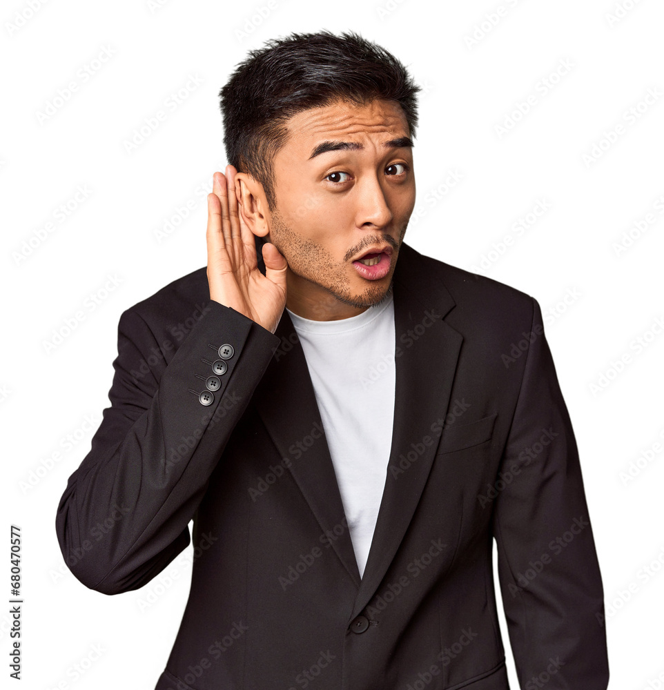 Young Chinese man in business suit in studio trying to listening a gossip. Young Chinese man in business suit in studio trying to listening a gossip.