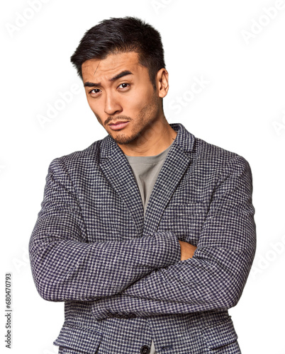 Young Chinese man in studio background suspicious, uncertain, examining you.